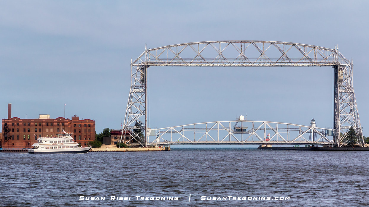 Vista Fleet's sightseeing cruise boats are a common sight on the water around Duluth, Minnesota. The Vista Star sits in Duluth Bay, waiting for the Aerial Lift Bridge to rise. Then it can travel through the Ship's Canal and out onto Lake Superior. 