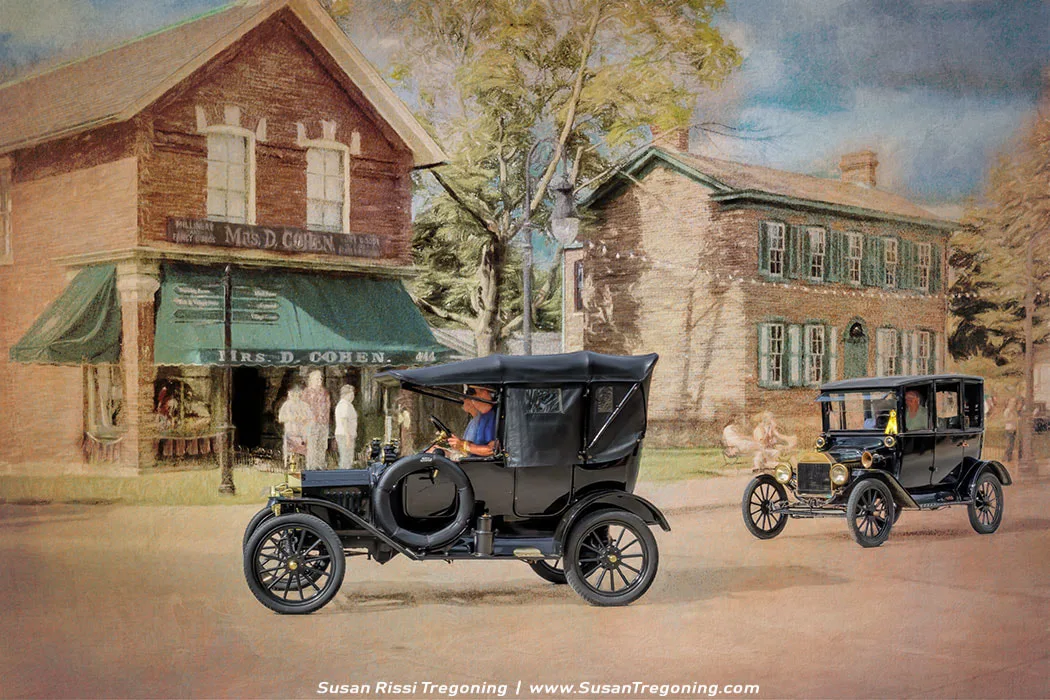 Two early Ford Model T automobiles travel down a village street lined with historic buildings. One car is an open‑top touring model and the other a closed‑top version, both rendered with a soft, painterly effect that emphasizes their rounded fenders, tall narrow wheels, and upright silhouettes. The storefront marked “Mrs. D. Cohen” with green awnings stands on one side of the street, while a brick house with green shutters anchors the other, creating the feel of an early‑20th‑century small‑town scene brought to life through digital illustration.
