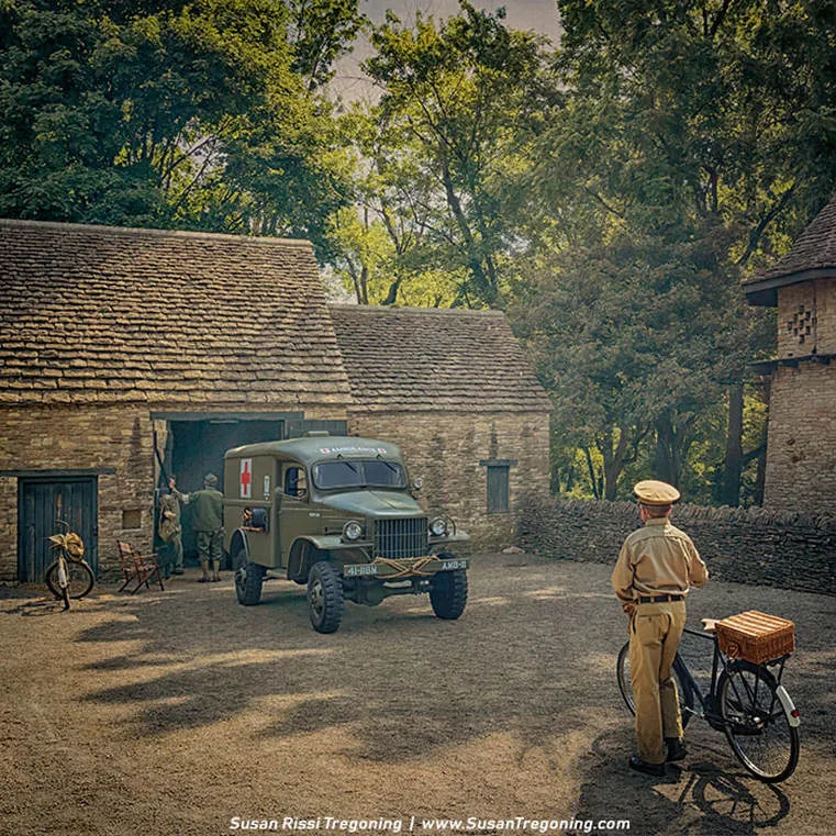 The 1941 WC‑27 ambulance waits in front of a rough‑hewn stone barn, its olive‑drab body softened by the muted light of an overcast day. The red cross on the door stands out sharply against the weathered stones, a quiet signal of urgency in an otherwise still moment. Soldiers in World War II–era uniforms gather near the barn entrance, their postures relaxed but purposeful, as if caught between duties. One figure stands apart with a bicycle fitted with a wicker basket, watching the scene with a calm, observant stillness. The uneven slate roofs, the thick stone walls, and the trees rising behind the buildings wrap the moment in the atmosphere of a wartime village—quiet, tense, and deeply human.

The scene has a cinematic quality, almost as if time has paused just long enough to let the viewer step into the story.