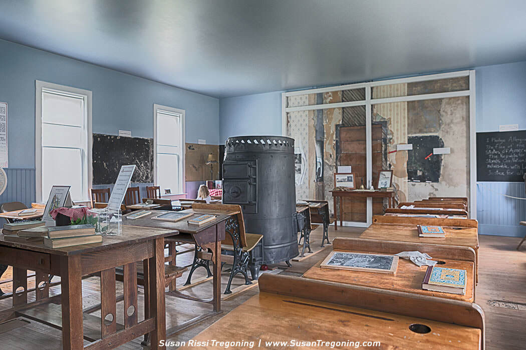 Inside the First School of De Smet, wooden desks, slate boards, and a central cast‑iron stove recreate the classroom where early Dakota Territory students learned during the years Laura Ingalls Wilder wrote about.