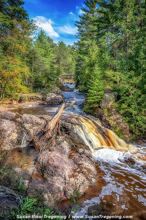A late‑summer view of the Amnicon River flowing over an unnamed waterfall in Amnicon Falls State Park, surrounded by lush green forest.