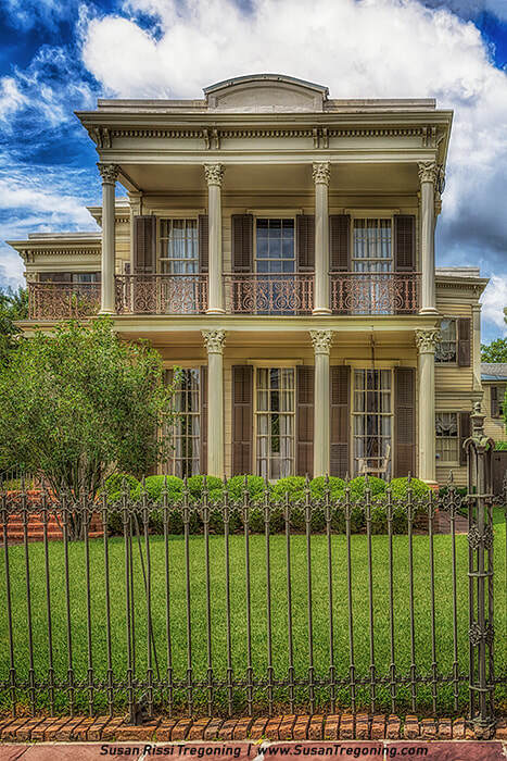 The Archie Manning House features tall classical columns, shuttered windows, and ornate iron railings, rising above its manicured lawn and decorative wrought‑iron fence.