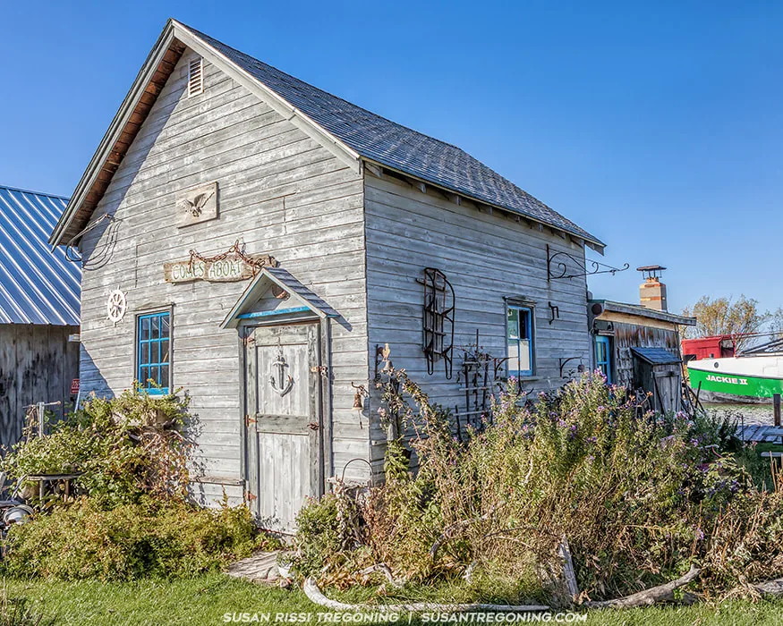 Natural‑wood building labeled “Comes Aboat” at Bell Marina, with the Jackie II fishing boat visible in the background near the docks.