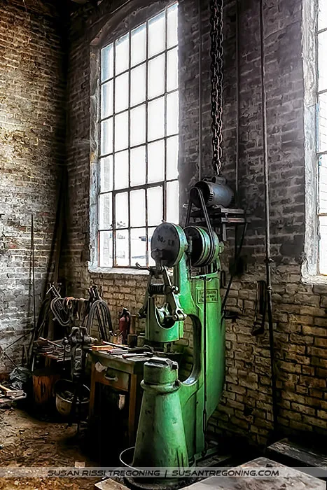 The Little Giant power hammer anchors this corner of the Soule Steam Feed Works shop, its cast‑iron frame and worn surfaces echoing decades of blacksmithing and steam‑era craftsmanship.