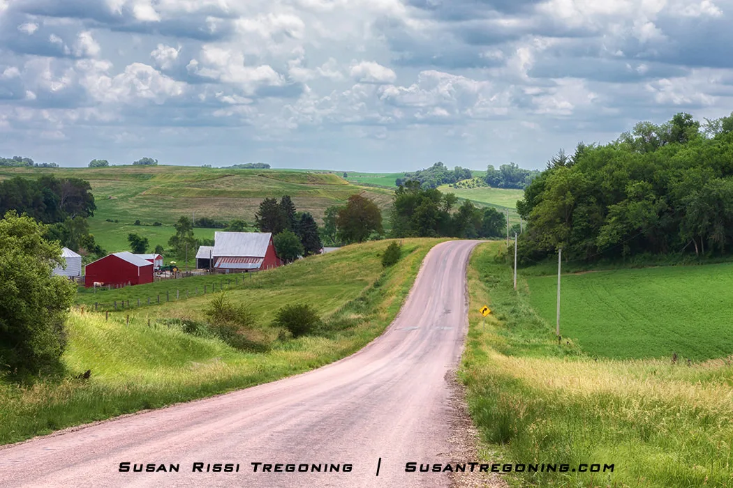 A view of a rural Iowa farm scene along the Orchard Ridge Loop on the Loess Hills National Scenic Byway. The landscape includes agricultural fields and farm structures within the surrounding Loess Hills terrain.