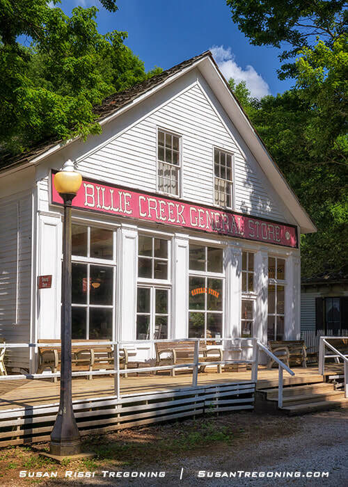 The Billie Creek General Store, a historic wooden building with front‑facing windows and simple board‑and‑batten siding, standing among green trees at Billie Creek Village after being relocated from the former Quaker community of Annapolis.