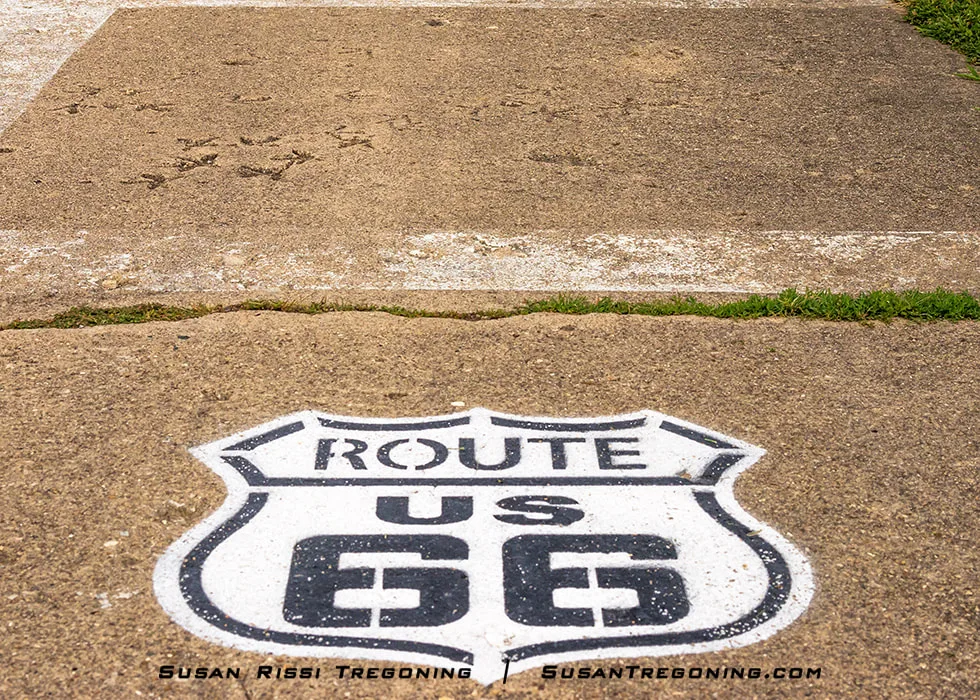 A close‑up view of a Route 66 shield and the 100‑plus‑year‑old turkey tracks that are permanently imprinted into the roadway on the historic 1926–1930 alignment near Nilwood, Illinois.