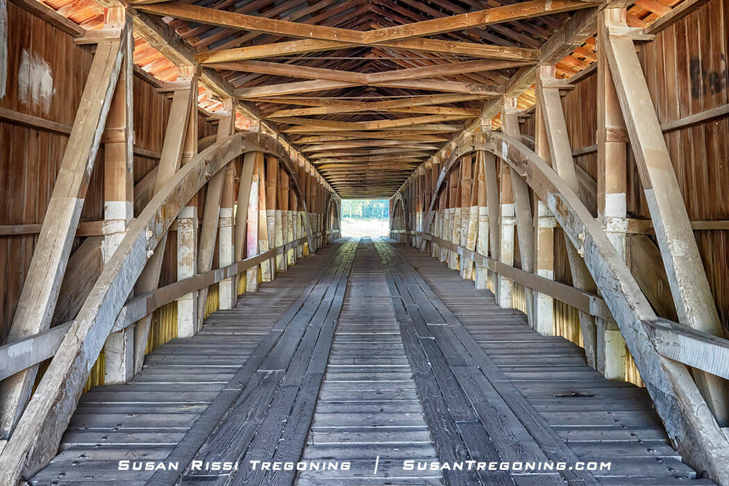   
The interior of the Mansfield Covered Bridge shows J. J. Daniels’ symmetrical burr arches, with curved wooden supports rising along the length of the span.