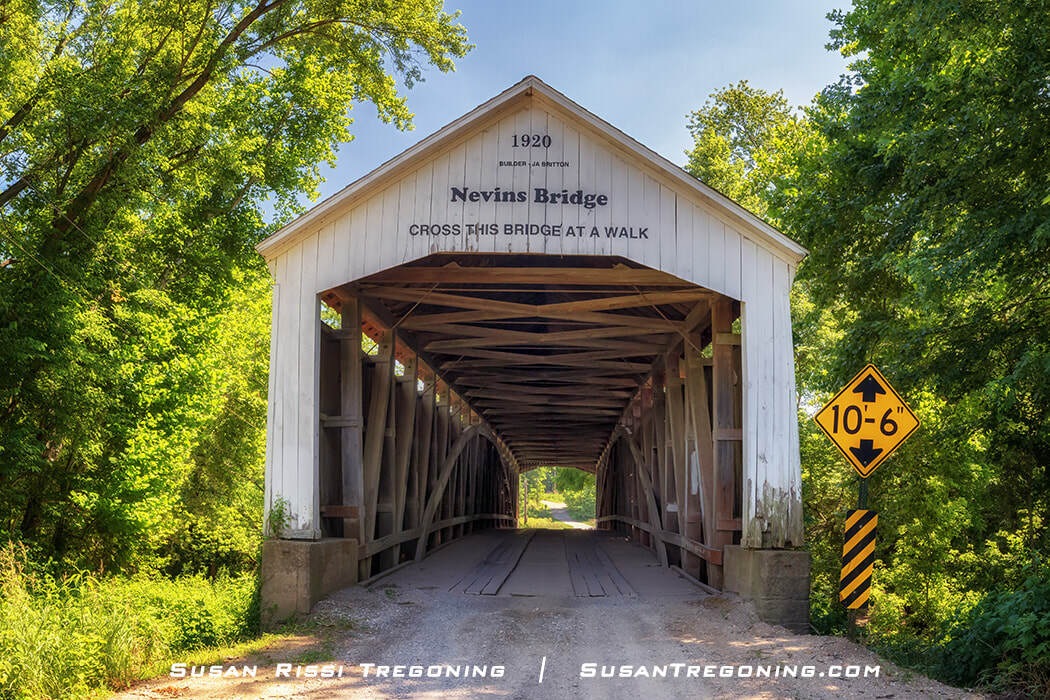 Nevins Covered Bridge, built in 1920 as the final covered bridge constructed by J.A. Britton and the last historic bridge built in Parke County, Indiana, shown surrounded by dense green trees with a clearance sign beside the entrance.