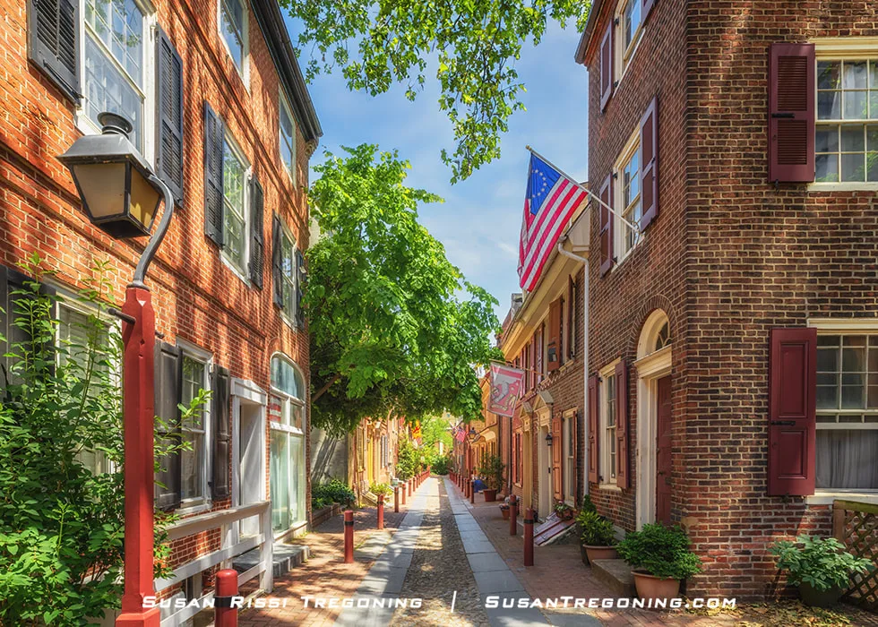 
A view of Elfreths Alley in Philadelphia showing a narrow historic street lined with brick row homes, cobblestones, and preserved architectural details.