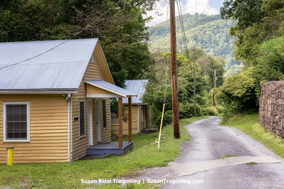 One‑story, four‑room houses built after 1920, known as the Philip McClung House and Rental, standing on a narrow, winding mountainside road above the ghost town of Thurmond, West Virginia.