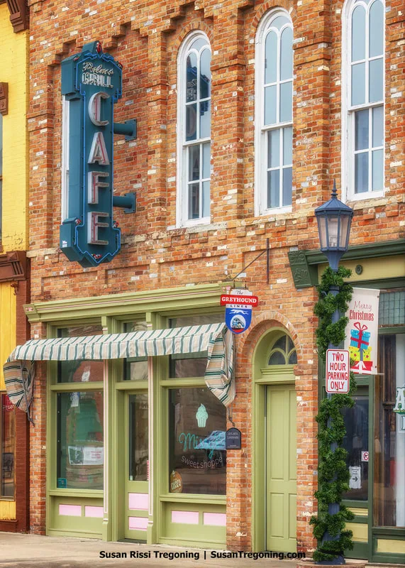 A close‑up view of the Palms Grill Cafe neon sign mounted on the front of the Downey Building in Atlanta, Illinois. Part of the building’s facade is visible along with the old Greyhound sign displayed near the entrance.
