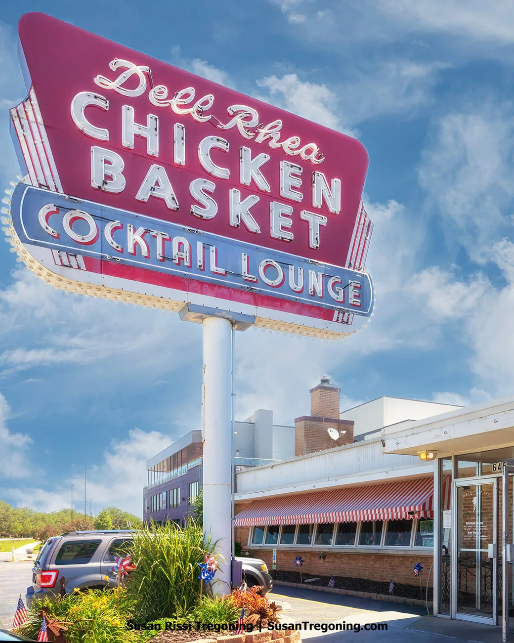  —
Retro neon sign for Dell Rhea’s Chicken Basket mounted above the restaurant building under a partly cloudy sky.