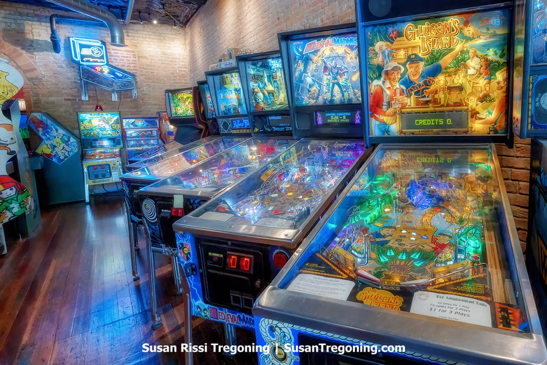 Vintage pinball machines are lined up inside Arcadia, the playable Video Arcade Museum in McLean, Illinois. A Gilligan’s Island pinball machine is positioned at the front of the row, with additional classic machines visible behind it.