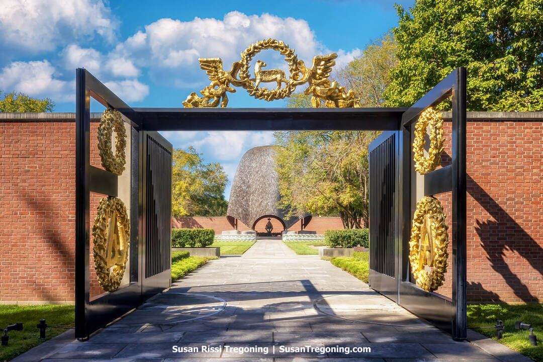 Phillip Johnson’s Roofless Church in New Harmony is framed by its open‑air brick entryway, where a sculptural arch leads into the circular courtyard beyond. The modernist structure rises against a backdrop of trees, its clean geometric lines and open sky emphasizing the chapel’s design as a contemplative space without a traditional roof.