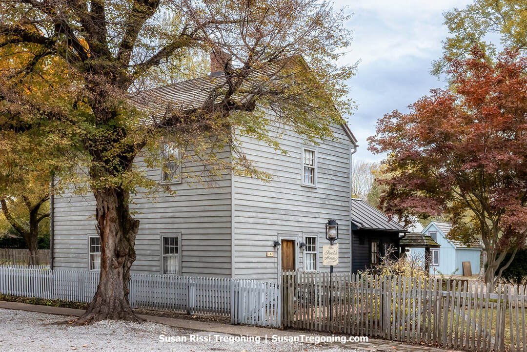 Poet’s House, New Harmony, Indiana —  
The gray clapboard Poet’s House stands behind its white picket fence beneath autumn trees, a simple two‑story dwelling that reflects the early New Harmony community’s blend of craftsmanship, scholarship, and everyday life.