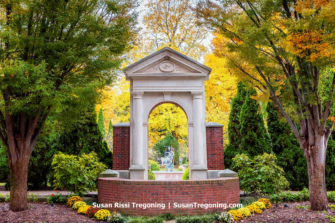 The 1822 stone archway rises above autumn gardens in Church Park, framing the modern sculpture beyond it. Once part of the early Harmonist community, the arch now stands as a symbolic threshold between New Harmony’s utopian past and its enduring spirit of renewal.