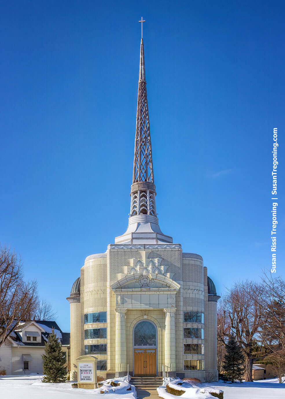 Art Deco Tyson Methodist Temple in Versailles, Indiana, built of glazed terracotta brick with a tall cast‑aluminum steeple, shown with snow on the ground.