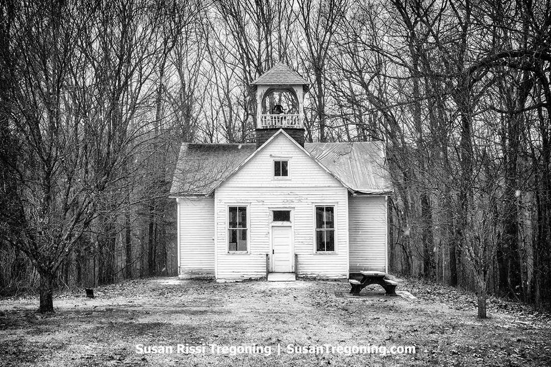 Black‑and‑white photo of the Walnut Grove School, a historic one‑room schoolhouse at Muscatatuck Park in North Vernon, Indiana, shown from the front with its simple rectangular structure and small bell tower.