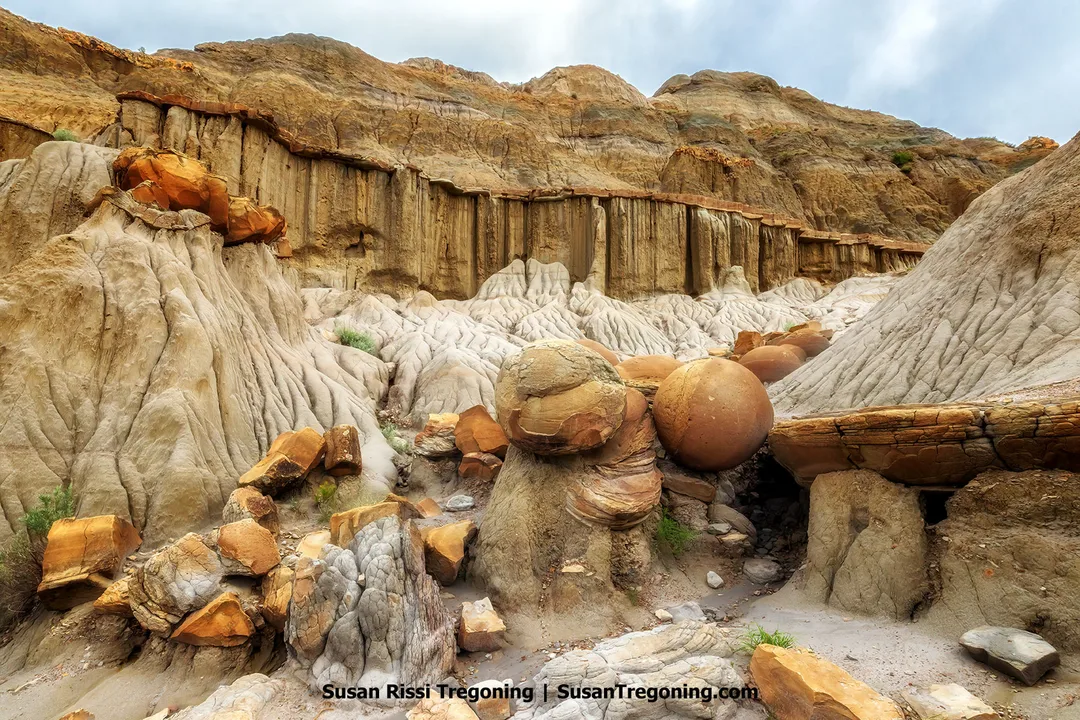 Scenic view of banded cliffs and sculpted clay slopes in the North Unit of Theodore Roosevelt National Park, where near-perfect sandstone cannonball concretions lie exposed among weathered formations in the North Dakota Badlands.