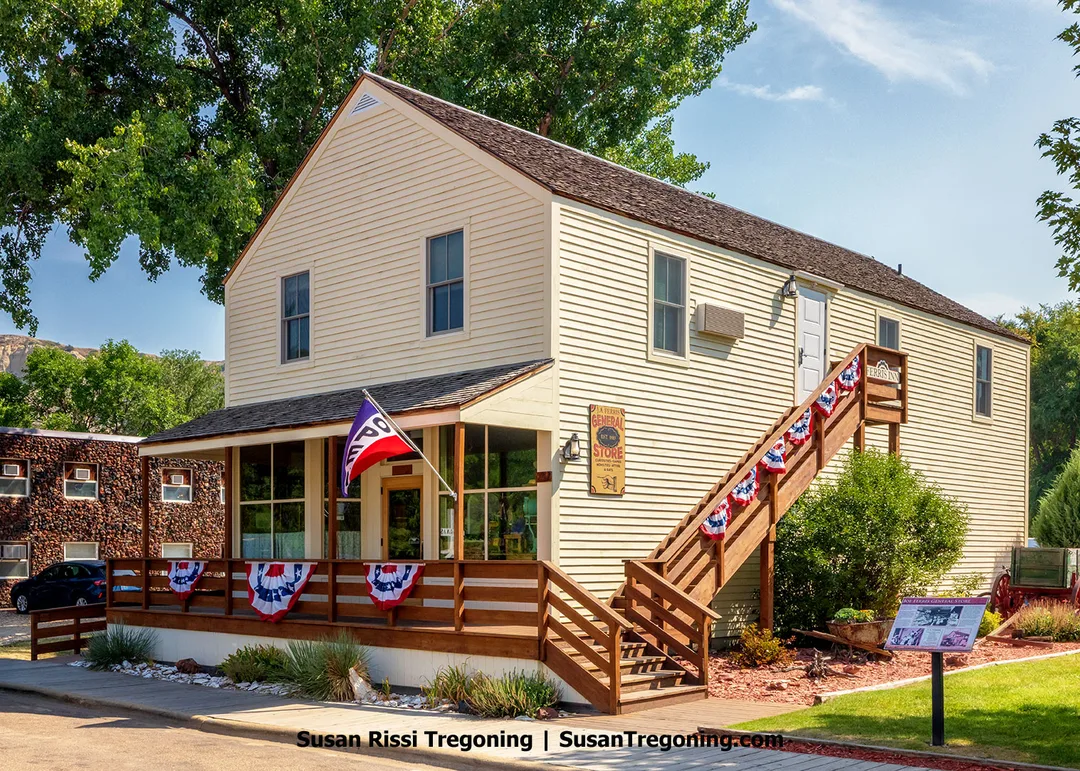 The Joe Ferris General Store in Medora, North Dakota, built in 1885, features cream‑colored siding, a wooden porch decorated with patriotic bunting, and an exterior staircase. Once a frontier hub of commerce, the store is known for hosting Theodore Roosevelt in an upstairs room during his visits to town.