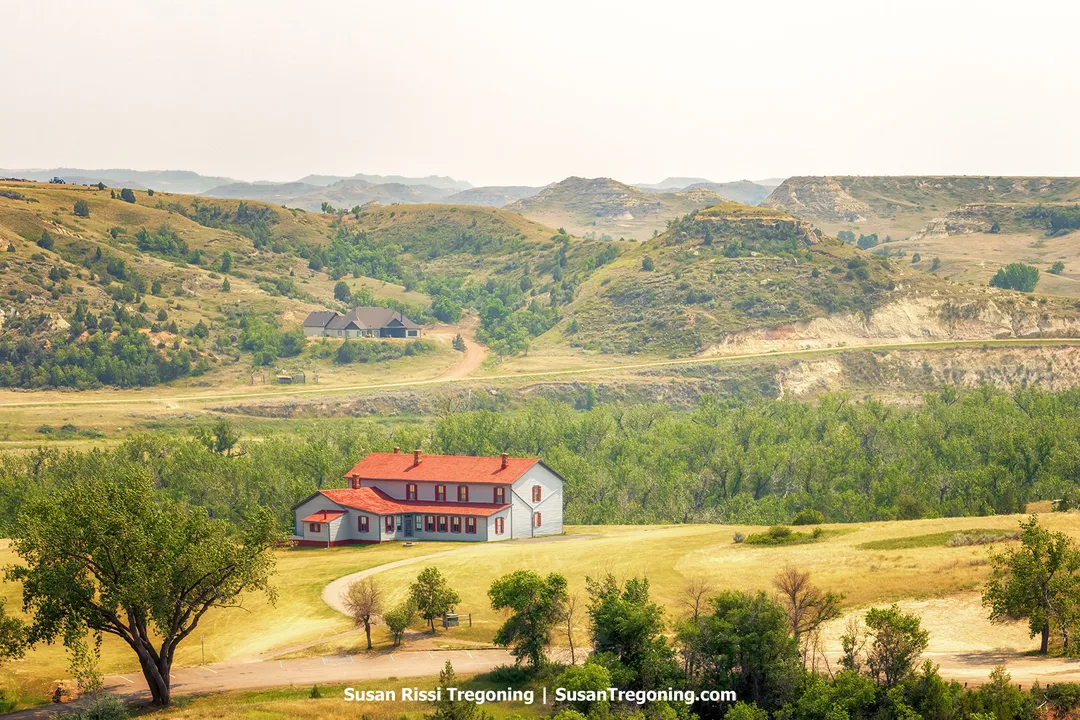 The historic Chateau de Mores, a two‑story mansion with red roofs and grey siding, stands on a hill overlooking the Badlands near Medora, North Dakota. Built in 1883 by the Marquis de Mores as a summer home for his family, the chateau is preserved as a state historic site and open for tours.founder