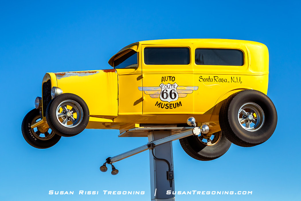 A bright yellow roadster high up on a post is the signage for the Route 66 Auto Museum in Santa Rosa, New Mexico.