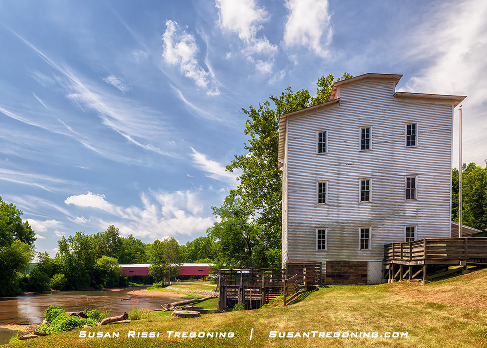 The historic white Mansfield Roller Mill sits on the Big Raccoon Creek in the small village of Mansfield in Parke County, Indiana. Just downstream in the distance is the historic 1867 Mansfield Covered Bridge.