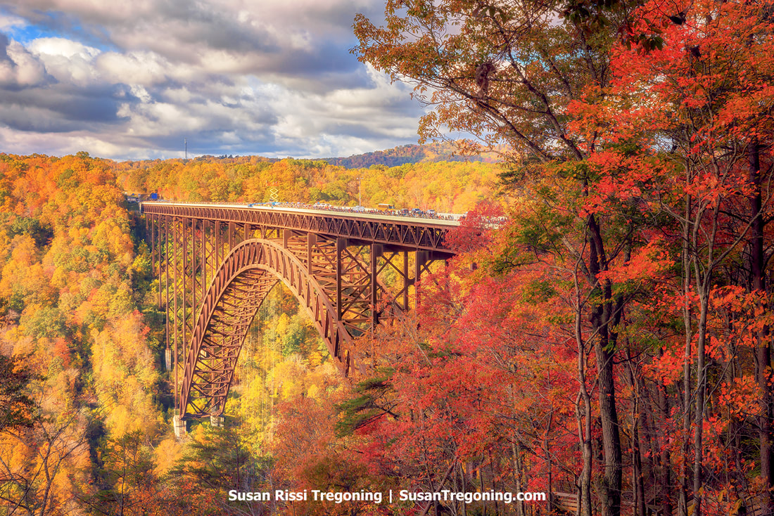 The New River Gorge Bridge is surrounded by stunning fall foliage as people pack the bridge during the Bridge Day festivities.